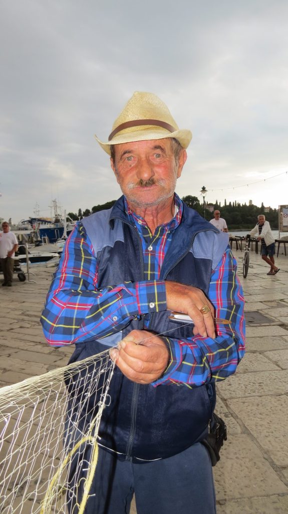 Edi Poropat demonstrira kako se krpa potrgana ribarska mreža / Snimio: Leon Tiska